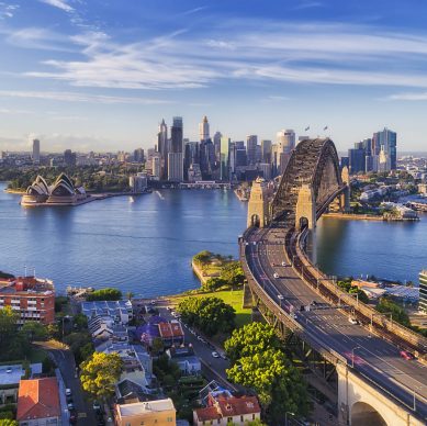 Cahill express way to the Sydney Harbour bridge across Sydney harbour towards city CBD landmarks in aerial eleveated wide view under blue morning sky.